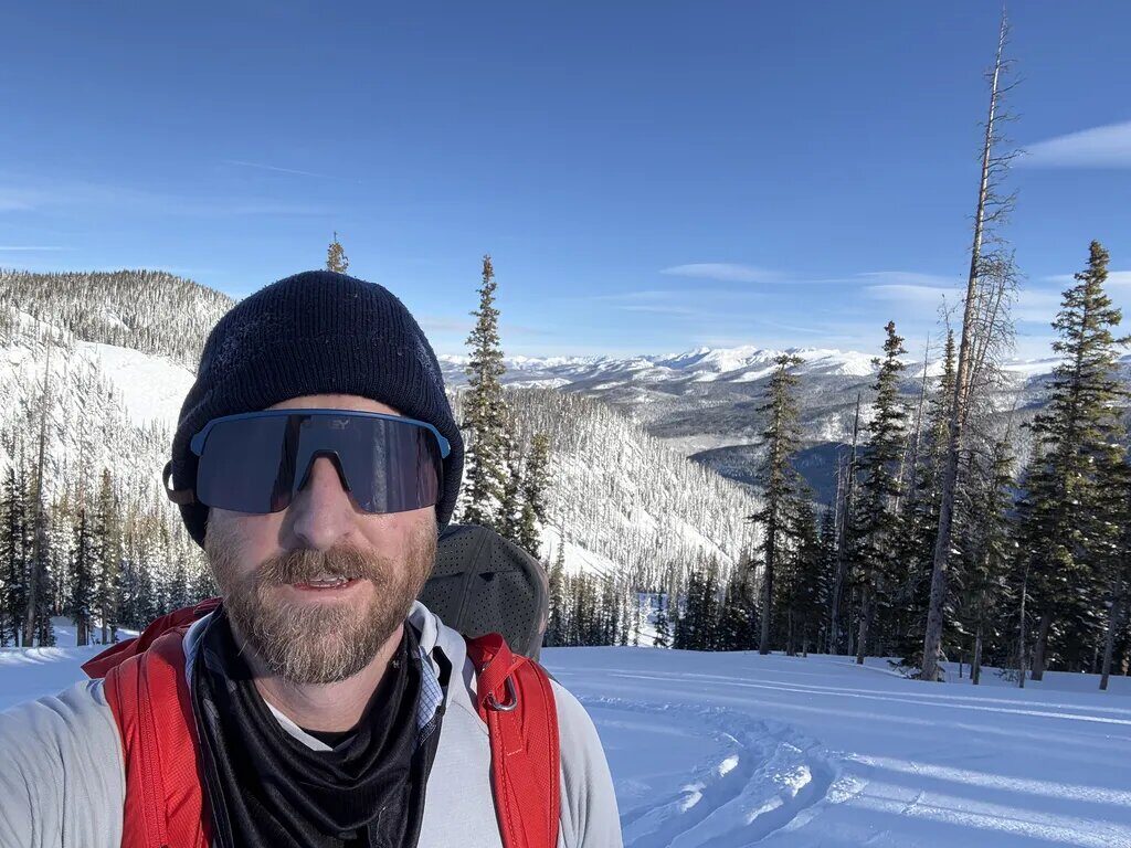 Ian with sunglasses and beanie on a snow-covered Colorado ridge