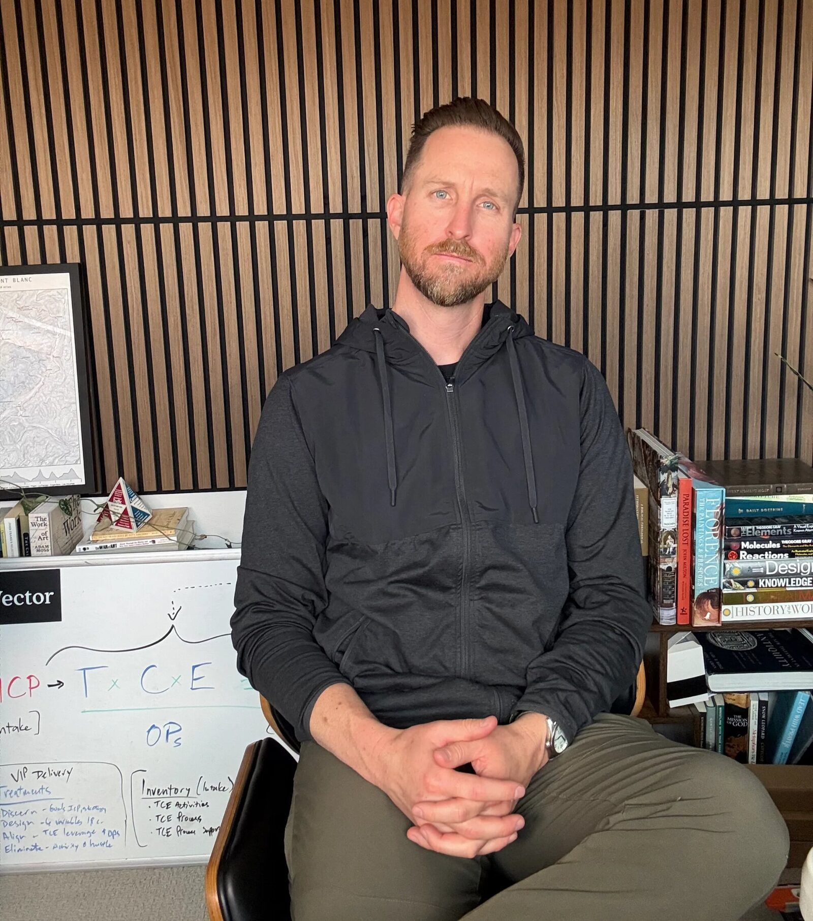 Ian Crafford sitting in his office in front of a whiteboard and bookshelf